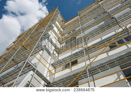 scaffolding near a new house, building exterior, construction and repair industry, white wall and window, yellow pipe