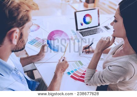 Beautiful Couple Of Designers In Casual Clothes Is Discussing Color Scale And Smiling While Working 