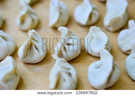 Close-up Of Chinese Uncooked Dumplings Placed On Wooden Board.  The Dumplings, Called Jiaozi In Chin