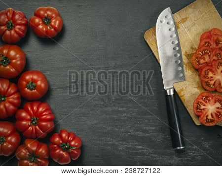 Photo Of A Table Top With Marmande Tomatoes, A Knife, And Slices On A Cutting Board.