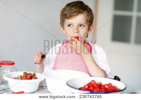 Little Blond Kid Boy Helping And Making Strawberry Jam In Summer. Funny Child Cleaning Berries And P