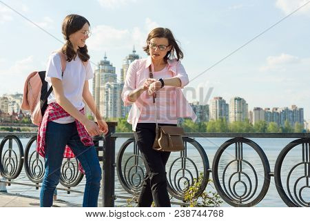 Mother And Daughter Teenager Walk Down The Street, The Woman Looks At The Clock, Rushes, Is Late, Qu