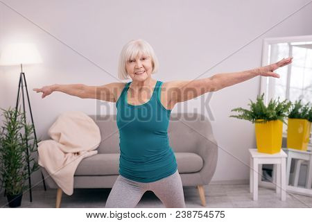 Morning Calisthenics. Upbeat Slim Woman Spreading Her Arms Wide And Smiling Happily While Doing Morn