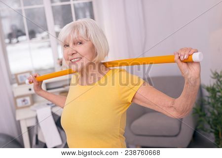 Invigorating Exercises. Upbeat Elderly Lady Posing For The Camera And Smiling Widely While Exercisin