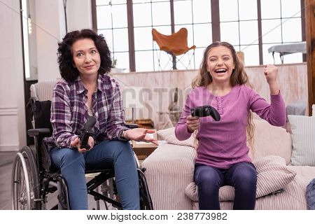 Game World. Jovial Incapacitated Woman And Girl Holding Controller While Gesturing