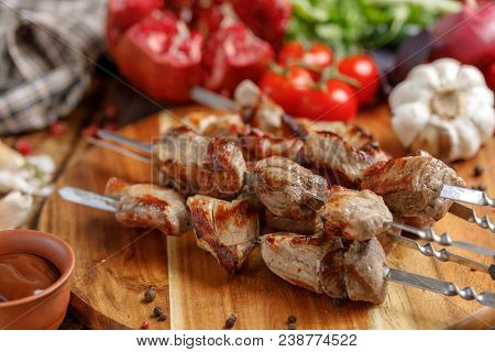 Juicy Appetizing Shish Kebabs Cooked On An Open Fire. Still Life With Textiles On A Wooden Backgroun