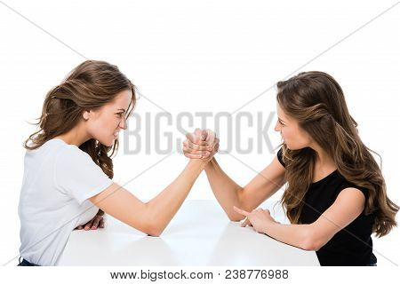 Side View Of Angry Twins Armwrestling At Table Isolated On White