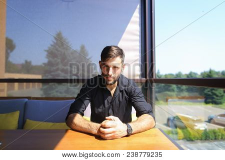 Young Male Caucasian Manager Sitting At Office On Sofa And Wearing Black Shirt. Concept Of Responsib