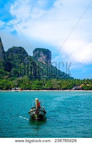 A Long-tail Boatd On A Calm Emerald Water In Front Of A Limestone Mountain At Railay Beach At Krabi,