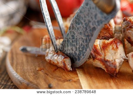 Juicy Meat Cooked On An Open Fire That Begins To Cut With An Original Knife And Fork.