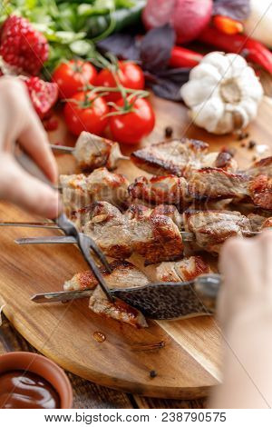 Rustic. Juicy Pork Is Cut With A Knife And Fork. Appetizing Shish Kebabs And Fresh Vegetables On A W