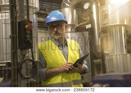 Industrial technician connected with tablet in recyling plant