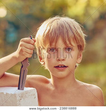 Portrait Of Young Smiling Athletic Boy With Throwing Knife, Image With Square Aspect Ratio And Warm 