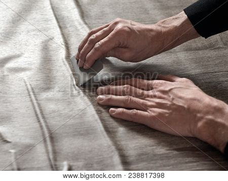 Closeup Of Carpenters Hands Removing Air From Self-adhesive Film