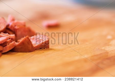 Pile Of Sliced Sausage On Wood Cutting Board.