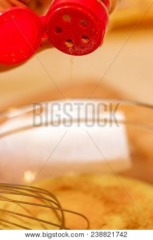 Adding Seasoning To Egg Mixture In Glass Bowl With Wisk.