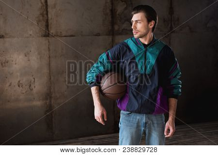 Stylish Young Man In Vintage Windcheater With Basketball Ball Looking Away