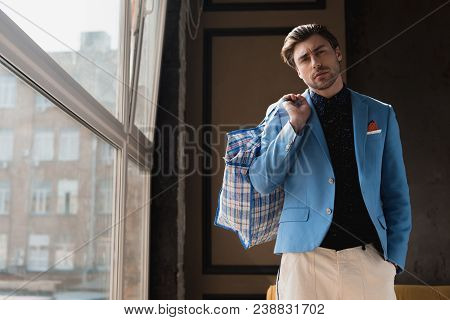Stylish Young Man With Vintage Zippered Duffle Bag On Shoulder