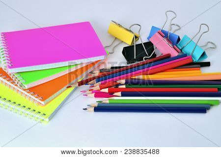 Color Pads, Pencils And Paper Clips On White Background