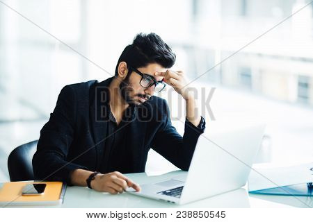 Photo Of An Indian Male Frustrated With Work Sitting In Front Of A Laptop In Modern Office