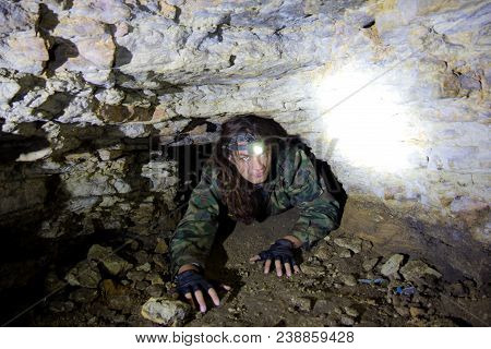 Man Explores Narrow Cavern Passage In Abandoned Underground Limestone Mine.