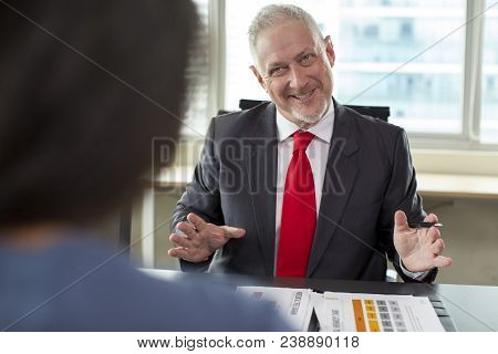Tensed But Smiling Business Owner Negotiating With Sales Manager. Middle Aged Man In Formal Suit Wit