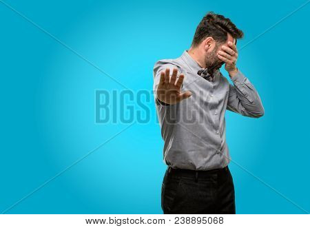 Middle age man, with beard and bow tie stressful and shy keeping hand on head, tired and frustrated