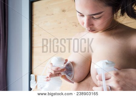 Happy And Young Asian Mother Is Pumping Breast Milk From Breast For Newborn Baby Feeding And Storage