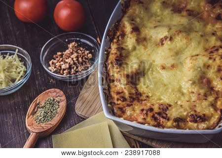Lasagne Layered Served On A Wooden Board With Fresh Tomatoes Alongside Cheese