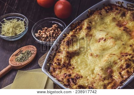 Lasagne Layered Served On A Wooden Board With Fresh Tomatoes Alongside Cheese