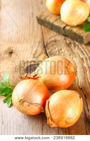 Yellow Onion With Parsley On A Wooden Table