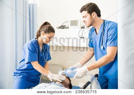 Team Of Male And Female Doctors Using An Ambu Bag For Ventilation To Unconscious Patient