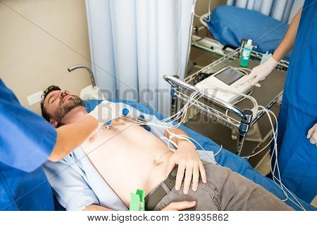 Hands Of Female Doctor Placing Ecg Electrodes On The Chest Of Patient With Nurse Standing By The Mac