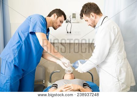 Two Doctors Performing Cpr On A Female Patient Using A Ambu Bag In A Hospital