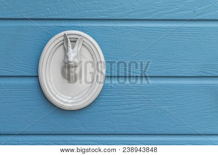 Ceramic Animal Head Or Rabbit Decoration On Blue Wooden Wall. Vintage Style Decoration Of White Rabb