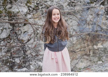 Laughting Cute Little Girl On Grey Rock Background.