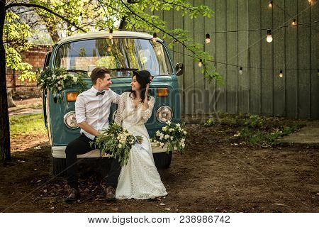 Cheerful Happy Young Couple Sit On The Bumper Retro-minibus