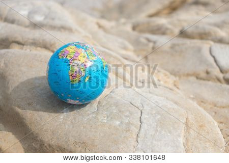 Small Earth Globe Lies On A Rock. Travel And Global Issues Conce