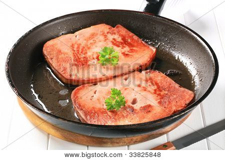 Duas fatias de carne do almoço na panela quente preta