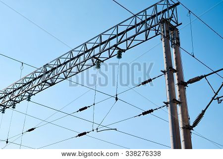 Power Electricity Wire For Trains Against Blue Sky. Close Up Of The Railway Electrification System