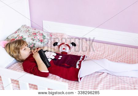 Little Blond Girl Lying In Bed In Her Room, Looking Angry, Upset. Children Misbehavior