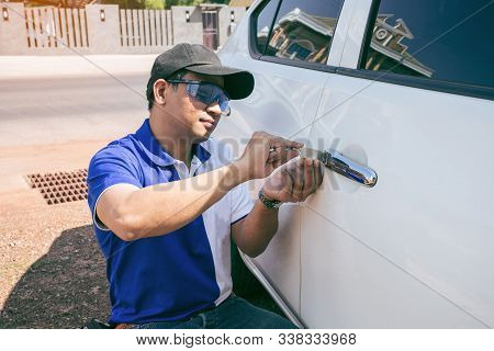 Young Man Opening White Car Door With Lockpicker. Professional Making Key In Locksmith