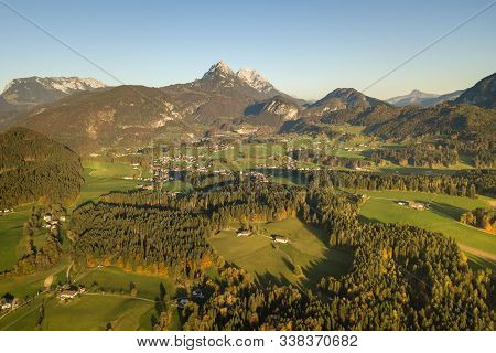 Aerial View Of Green Meadows With Villages And Forest In Austrian Alps Mountains.