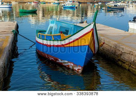The Traditional Boat In Malta Named Luzzu Is Moored Between Two Stone Plates. The Luzzu Is Placed In