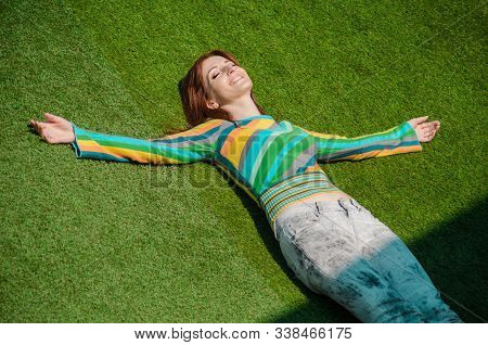 Cute Redhaired Caucasian Girl In Gray Jeans, Rainbow Blouse, Smiling Calm And Totally Happy, Lay On 