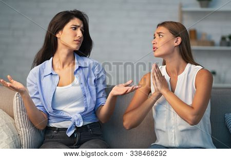 Bad Friendship. Girl Refusing To Do A Favor For Begging Friend Sitting On Sofa At Home. Selective Fo