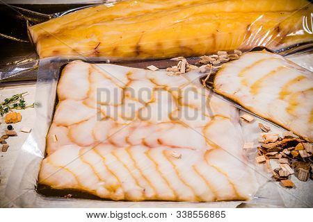White Smoked Fish In A Sealed Vacuum Package On The Background Of A Stack Of Packages