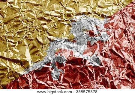 Bhutan Flag Depicted In Paint Colors On Shiny Crumpled Aluminium Foil Closeup. Textured Banner On Ro