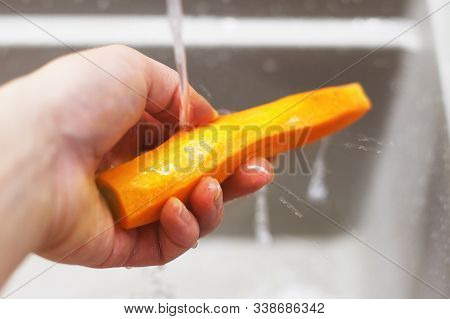 Woman Washes Carrots In The Kitchen. Raw Carrots