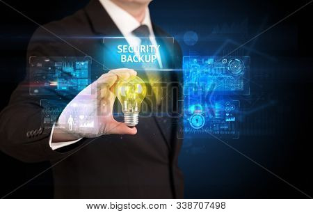 Businessman holding lightbulb with SECURITY BACKUP inscription, online security idea concept